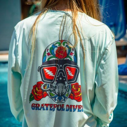 The back of a woman wearing the Grateful Diver Sugar Skull UV Shirt diving mask.
